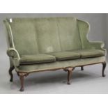 An early 20th century Queen Anne style wing back settee, upholstered in green velour, raised on