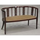 An Edwardian mahogany and line inlaid tub back salon settee with pierced splat supports, on square