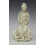 A Chinese blanc-de-Chine porcelain figure of Guanyin, Qing dynasty, modelled seated upon the back of