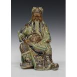 A Chinese stoneware figure of Guandi, late Qing dynasty, the god of war modelled seated on a