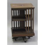 An Edwardian mahogany revolving bookcase, the two tiers with slatted sides, raised on a bracket