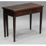 A George III mahogany fold-over tea table, the hinged top above an oak-lined drawer, on tapering