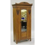 An Edwardian Art Nouveau walnut wardrobe with carved decoration, fitted with a mirrored door, on