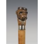 A late 19th century Malacca walking stick, the carved softwood handle modelled in the form of a