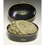 A 20th century barrister's wig, contained within an oval tole painted tin case, together with a Moss