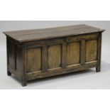 An 18th century oak coffer, the hinged lid above a four panel front, raised on stile supports,