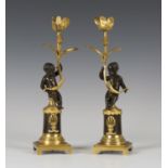 A pair of Regency brown patinated and gilt bronze candlesticks, each stem modelled as a putto