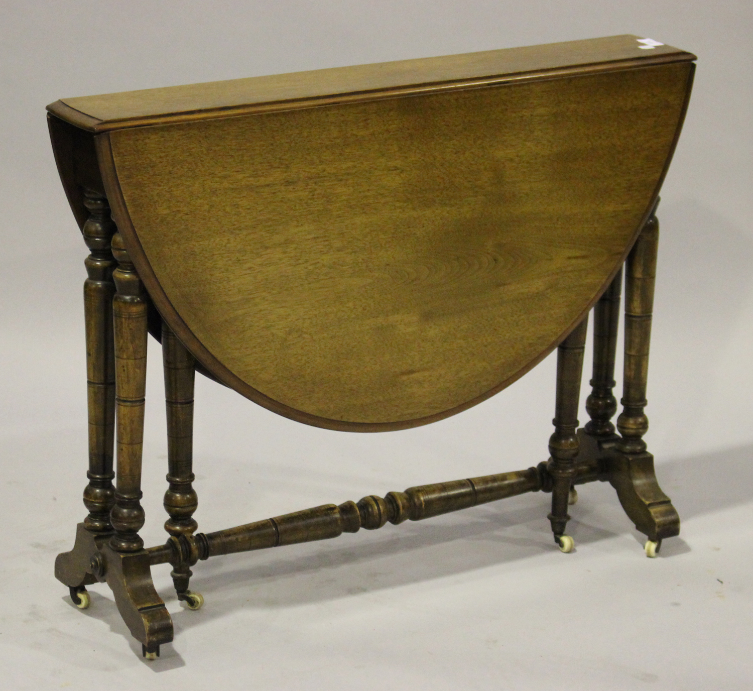 A late Victorian walnut oval Sutherland table, on turned supports and castors, height 70cm, width