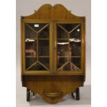 An Edwardian mahogany wall cabinet with inlaid decoration, fitted with a pair of glazed doors,