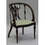 An Edwardian mahogany tub back bedroom chair with carved leaf decoration, raised on tapering legs,