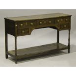 A late George III oak dresser base, the crossbanded top above an arrangement of five drawers and