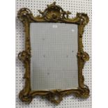 A late 19th/early 20th century Rococo Revival gilt painted composition wall mirror with a bevelled