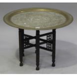 A late 19th/early 20th century Middle Eastern brass tray-top table, the tray with overall engraved