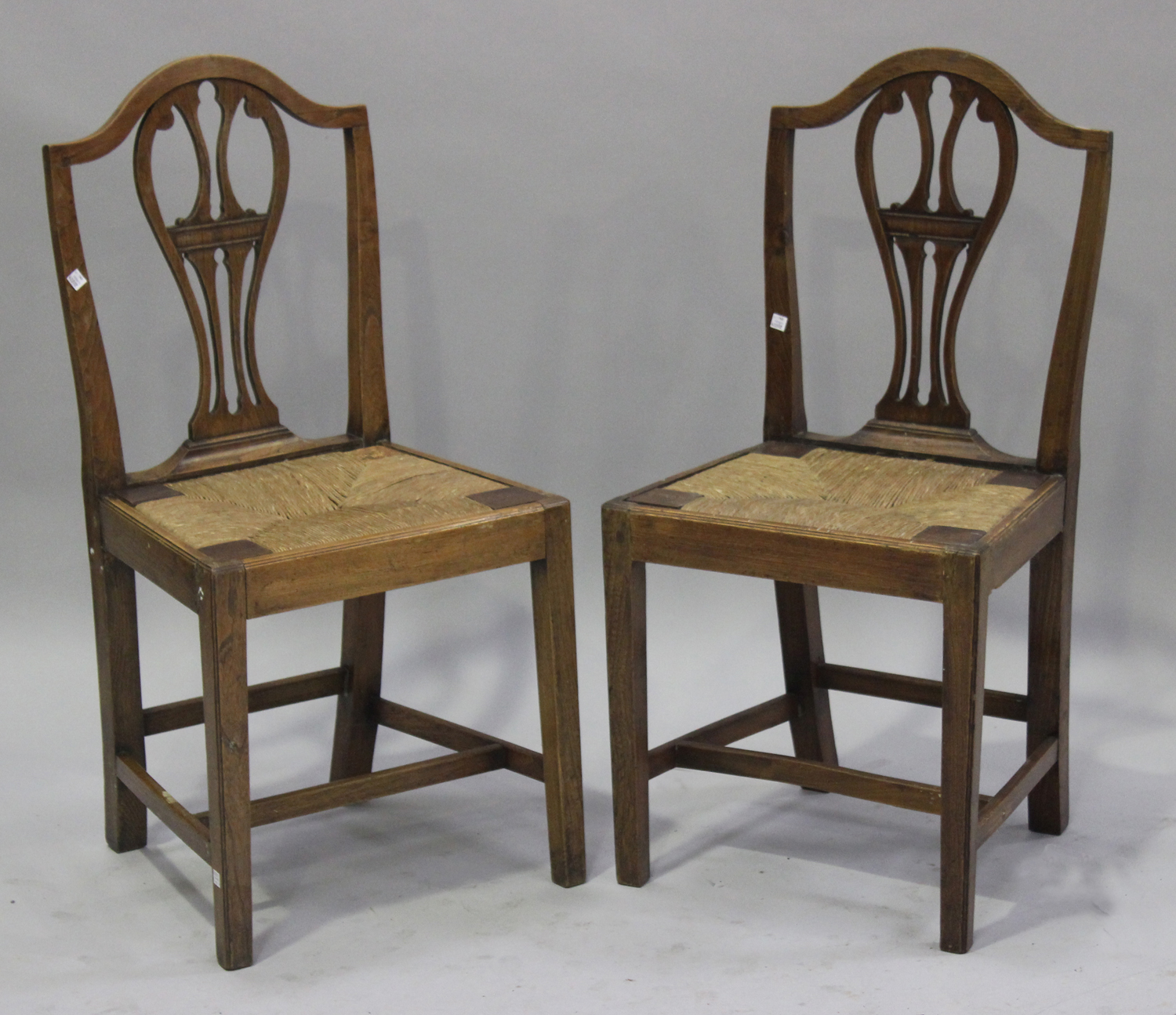 A set of six George III provincial elm dining chairs with carved and pierced splat backs above