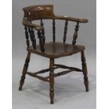 An early 20th century ash and elm tub back captain's armchair, the solid seat on turned legs, united