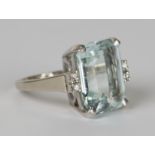 A 14ct white gold, aquamarine and diamond ring, claw set with a rectangular cut aquamarine between