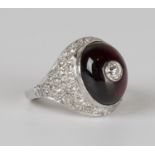 A French garnet and diamond ring, mounted with an oval cabochon garnet centred by a circular cut