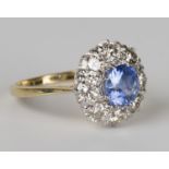 An 18ct gold, sapphire and diamond cluster ring, claw set with a cushion shaped sapphire within a