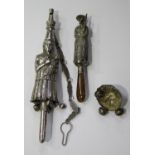 A white metal child's rattle, modelled as a mother holding her baby child, with whistle terminal,
