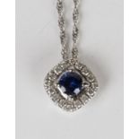 A white gold, sapphire and diamond cluster pendant, claw set with the circular cut sapphire within a