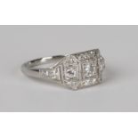 A platinum and diamond ring, mounted with three circular cut diamonds in square shaped settings