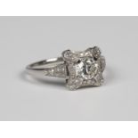 A platinum and diamond ring, claw set with the principal circular cut diamond in an open shaped