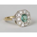 An 18ct gold, emerald and diamond ring, collet set with an oval cut emerald within an octagonal