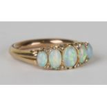 A gold, opal and rose cut diamond ring, mounted with a row of graduated oval opals and four pairs of