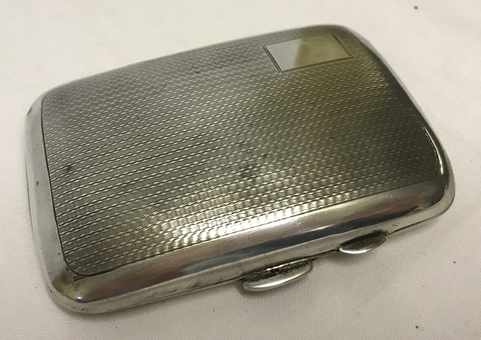 A small hallmarked silver cigarette case with engine turned detail and blank rectangular cartouche.