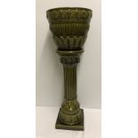 An olive green ceramic jardinere and stand.