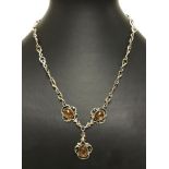 An ornate silver necklace set with 3 amber cabochons.