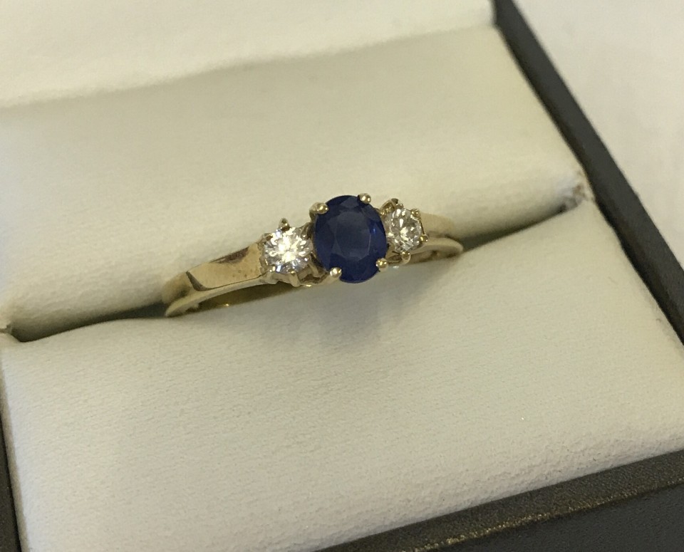 A 18ct gold dress ring set with central round sapphire and two diamonds either side.