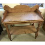 A vintage pine washstand with shaped top and turned legs.