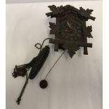 A small black forest style wall hanging clock with pendulum and weight.