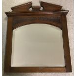 A small dark oak framed hall mirror with carved detail and bevel edged glass.