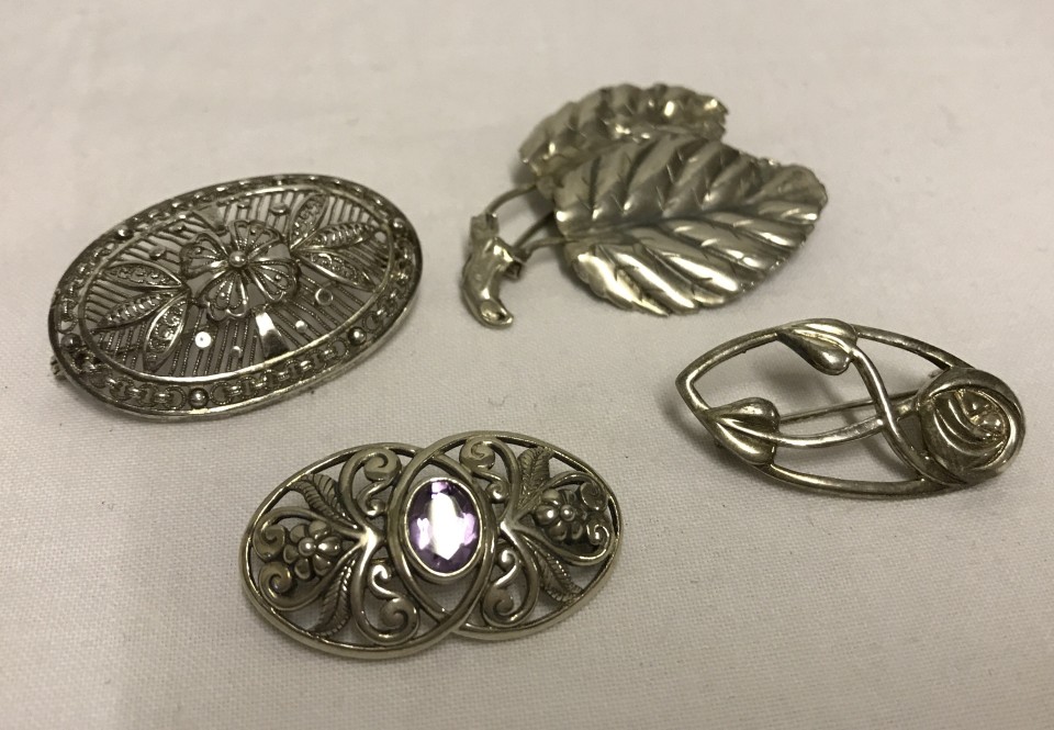 4 silver and white metal brooches.