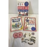 A collection of Red cross first aid manuals, metal and cloth badges.