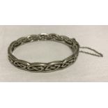 A 925 silver celtic design hinged bangle with safety chain.