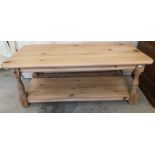 A modern pine rectangular coffee table with lower shelf and turned legs.