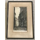 A framed and glazed black and white etching by Cecil Tatton Winter of a street scene.