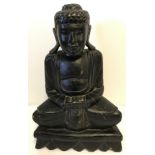 A carved wooden figurine of a Buddha, painted black.