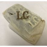 A quantity of 11 L.G. metal letter badges.