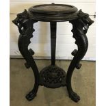 A vintage ebonised oriental wooden plant stand with carved dragon legs.