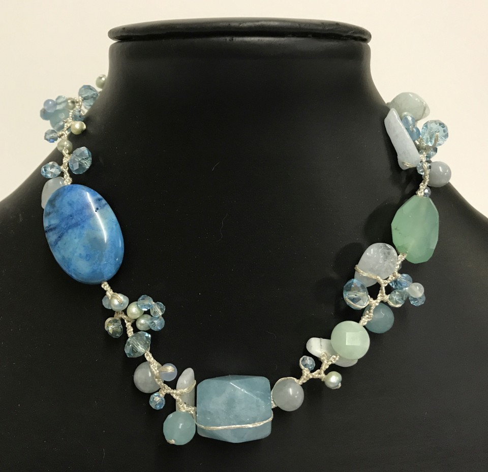 A modern contemporary design necklace made with blue tone natural stones, pearls and glass beads.