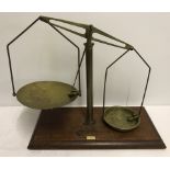 A set of brass shop weighing scales on a wooden plinth.