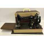A vintage Singer sewing machine with original attachments and rubber mat.