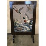 A vintage dark oak framed firescreen with ducks in flight tapestry.