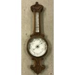 A vintage barometer with carved decoration and thermometer.