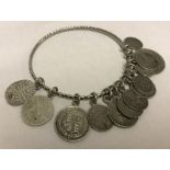 A white metal bangle with silver and white metal coin charms.