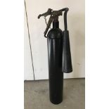 A vintage black fire extinguisher complete with hose and horn.